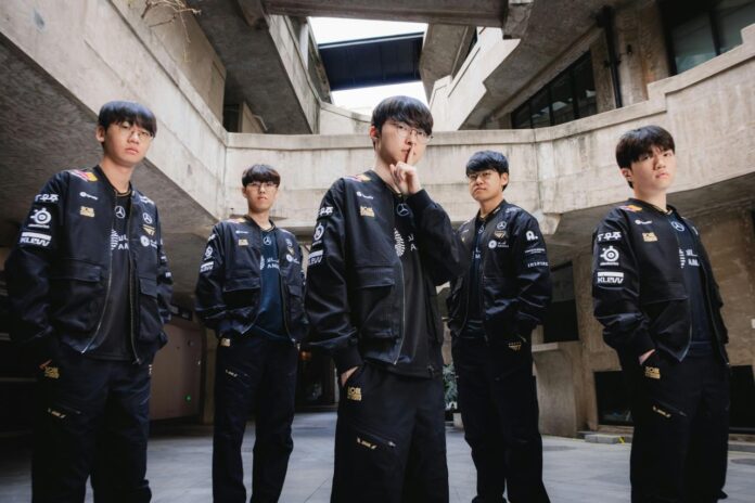 Five young men in matching black jackets stand together