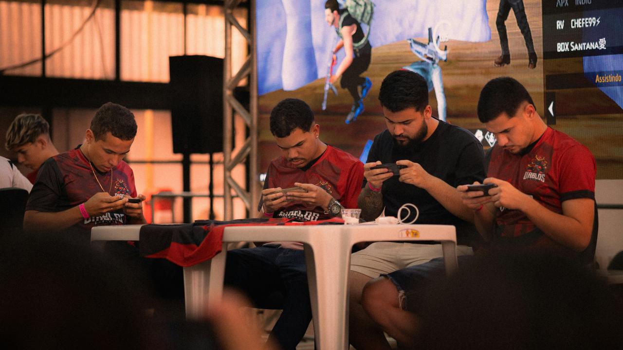 Four men playing mobile games at a table